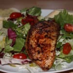 Tilapiafilet auf einem Salatbett mit Knoblauch Baguette